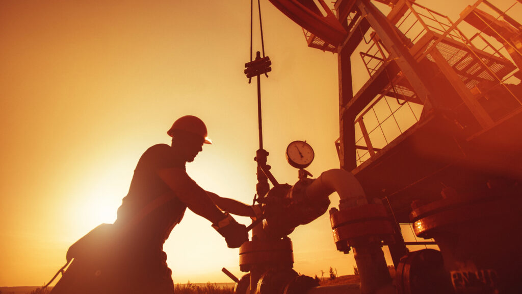 Oil worker is checking the oil pump on the sunset background.