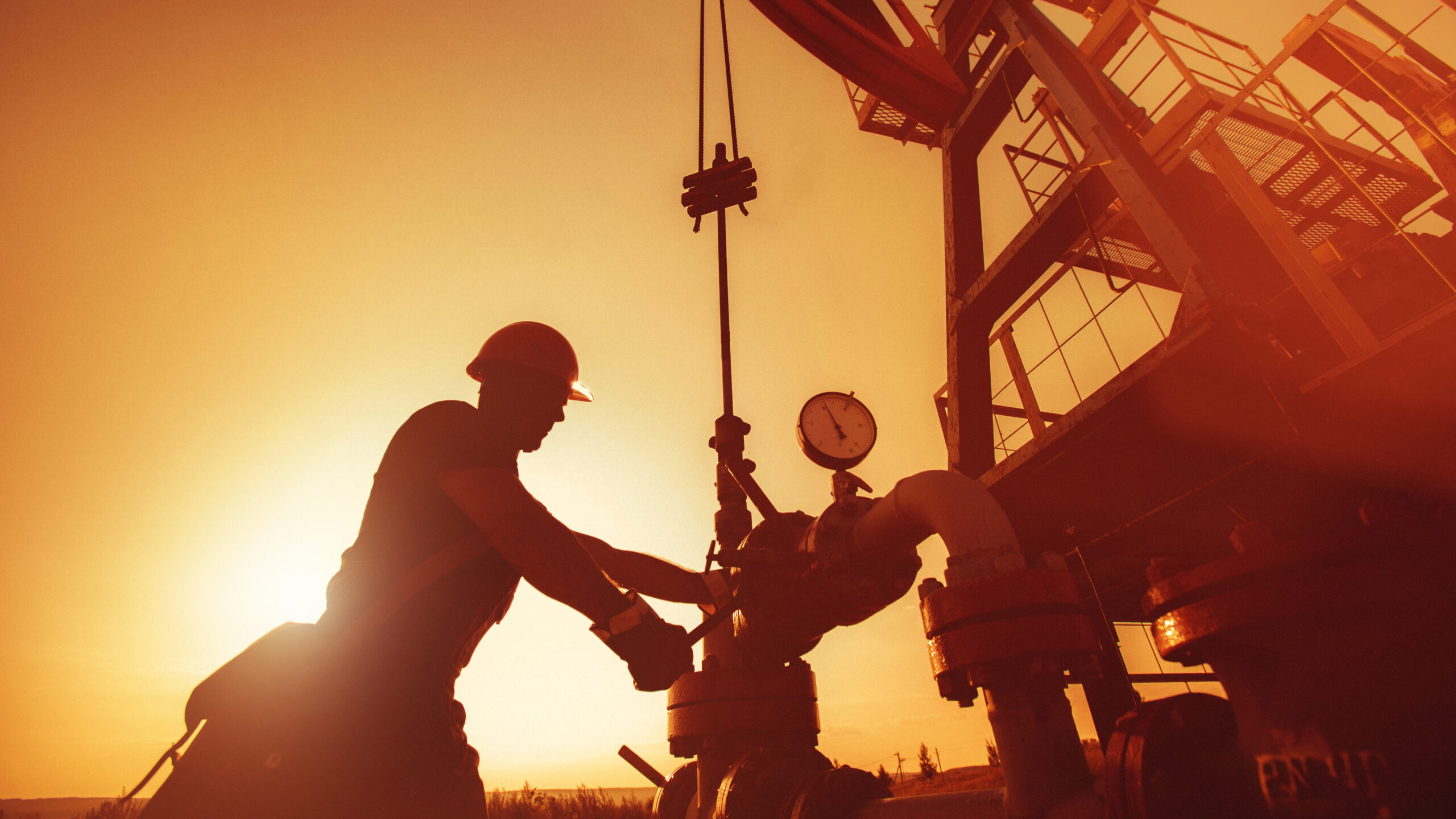 Oil worker is checking the oil pump on the sunset background.