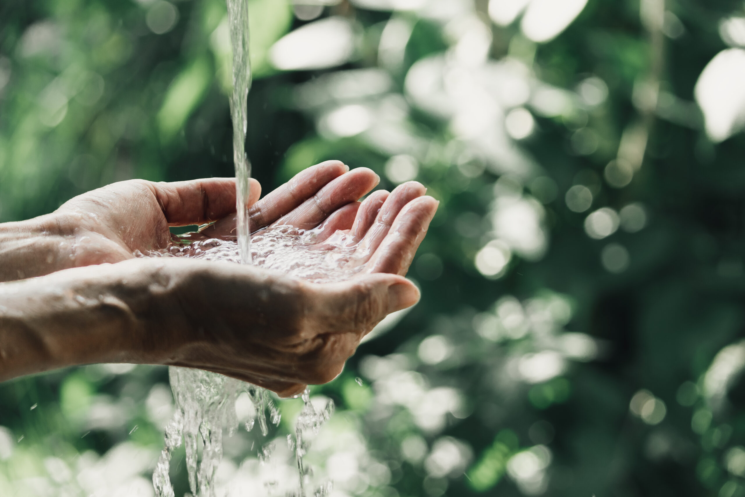 closeup water flow to hand of women for nature concept on the garden background.