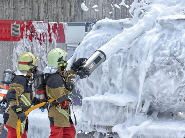 firefighters using foam to stop a fire