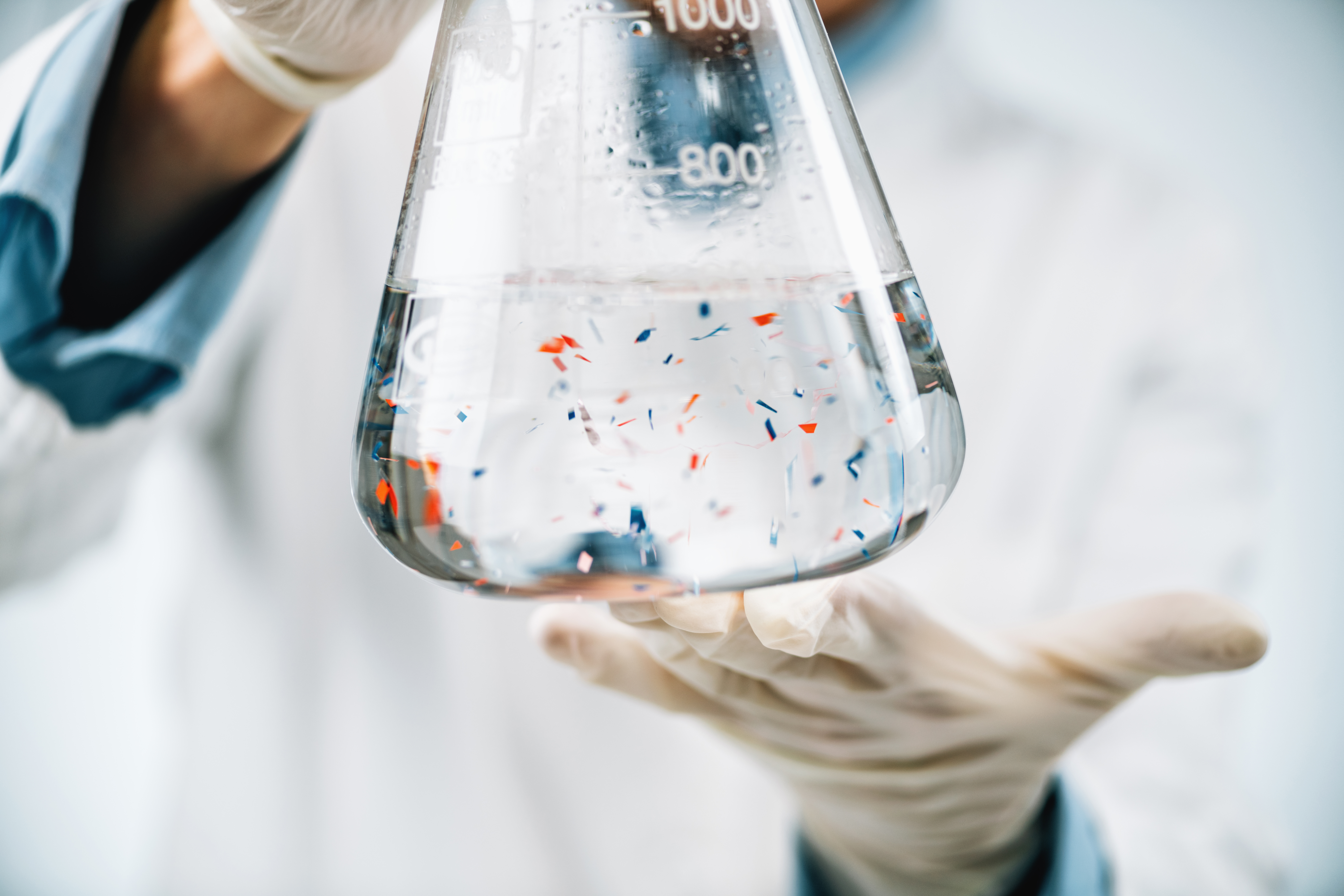 Scientist observing microplastics particles in a flask with a water sample.