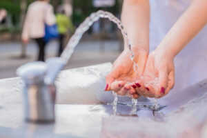 a woman washing her hands using a public water drinking fountain