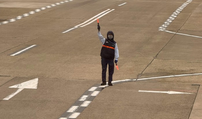 airport worker standing on a runway with lights
